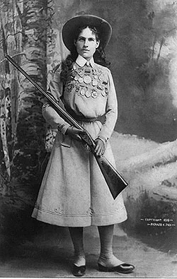 Full length portrait of Annie Oakley holding her gun